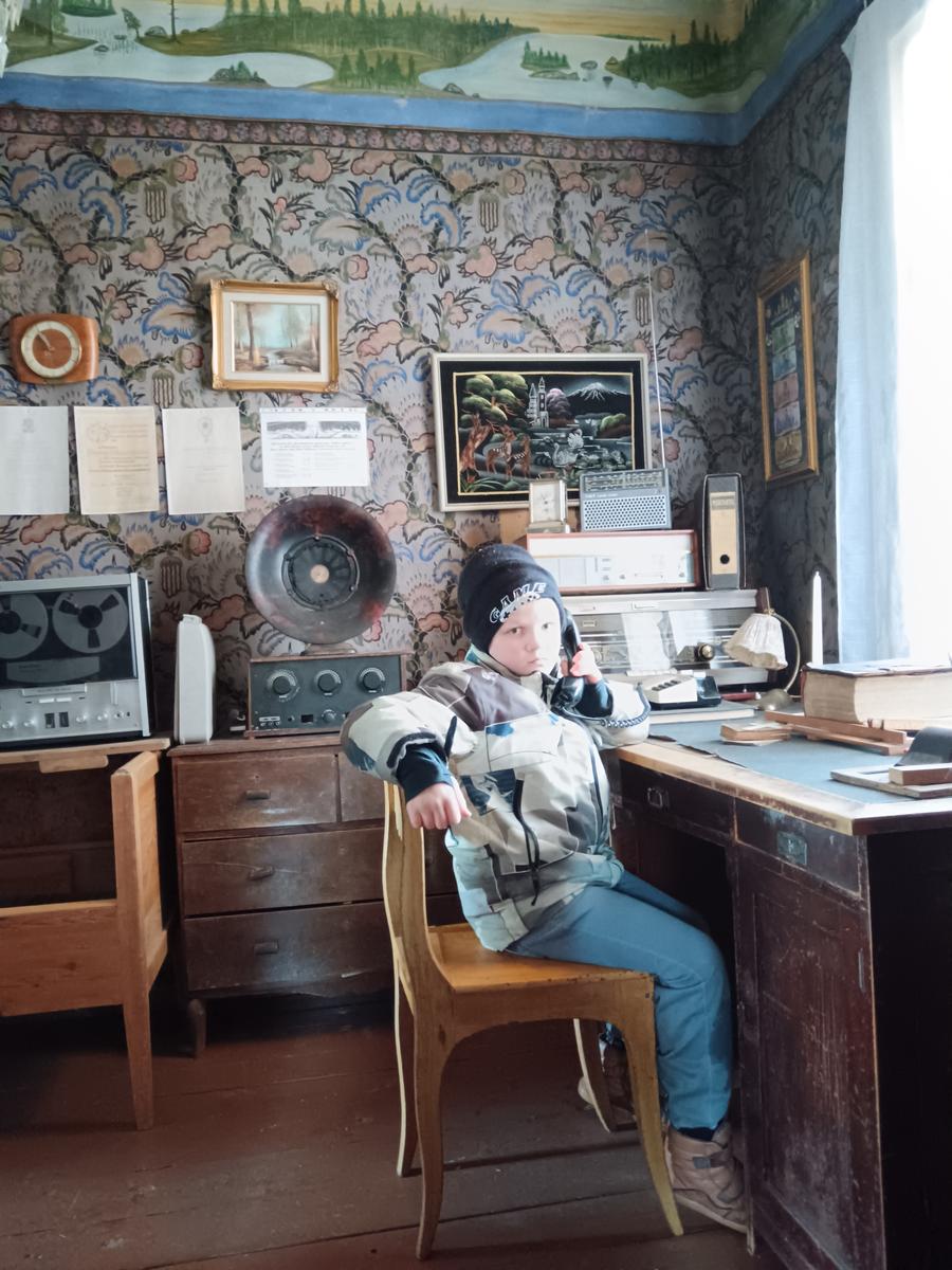 Poika vanhan puhelimen ja radioiden äärellä